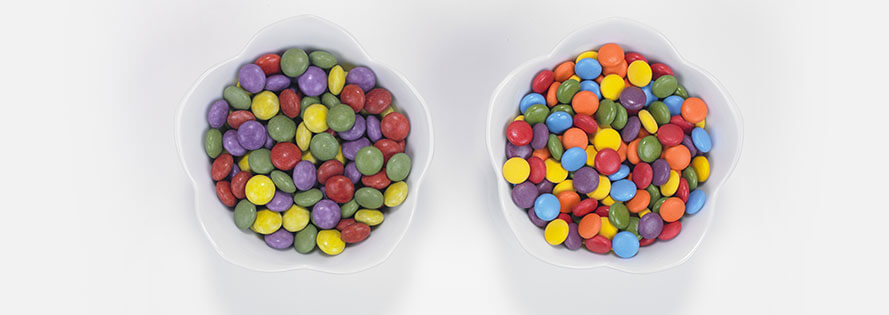 Two adjacent cereal bowls filled with coloful cereal.