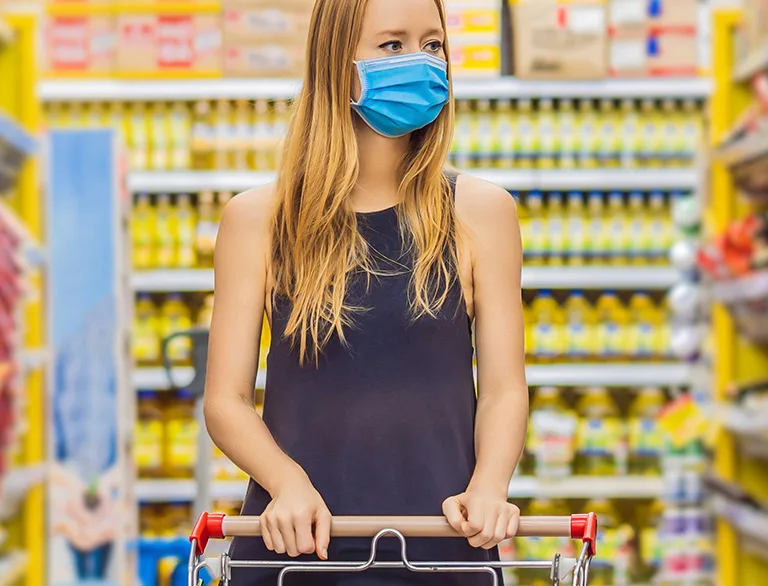 woman in mask grocery shopping post covid-19